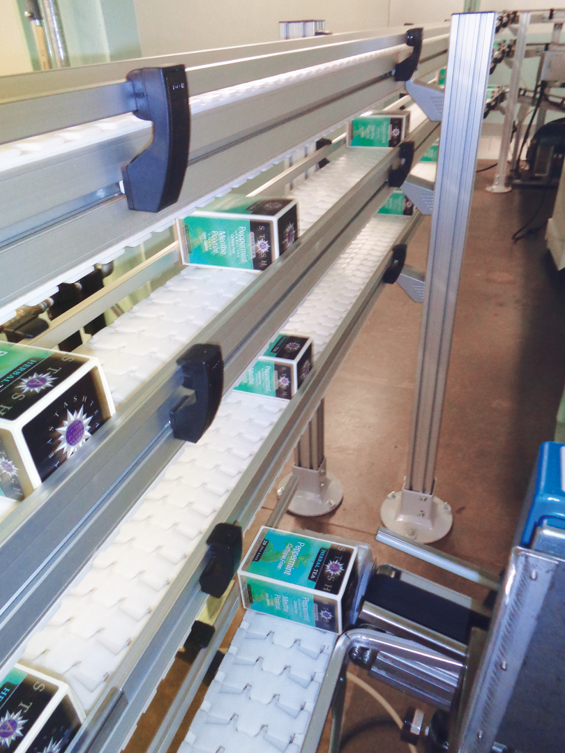 A series of pneumatic stops, escapements, and right-angle pushers ensure that cartons are released onto the trunk line at the ri
