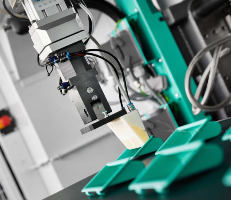 The 3D-printed gripper attached to the robot arm is designed to remove specially designed injection molded parts. Source: Arburg