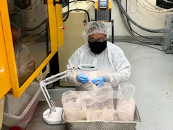 Trademark Plastics' cross-trained machine operator inspecting molded parts under magnification. Trademark Plastics' cross-trained machine operator inspecting molded parts under magnification.