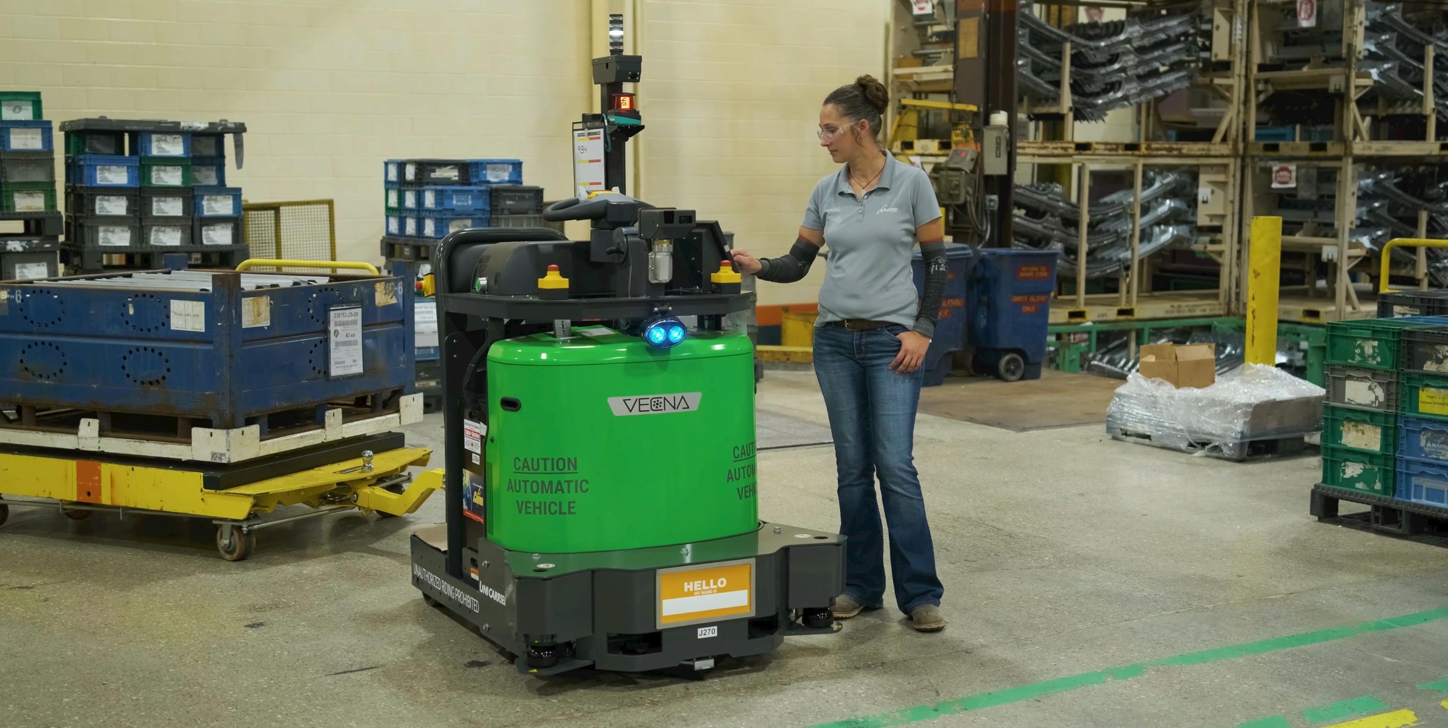 A warehouse employee programs a Vecna Robotics ATG Autonomous Tugger for its next task on the shop floor. Source: Vecna Robotics