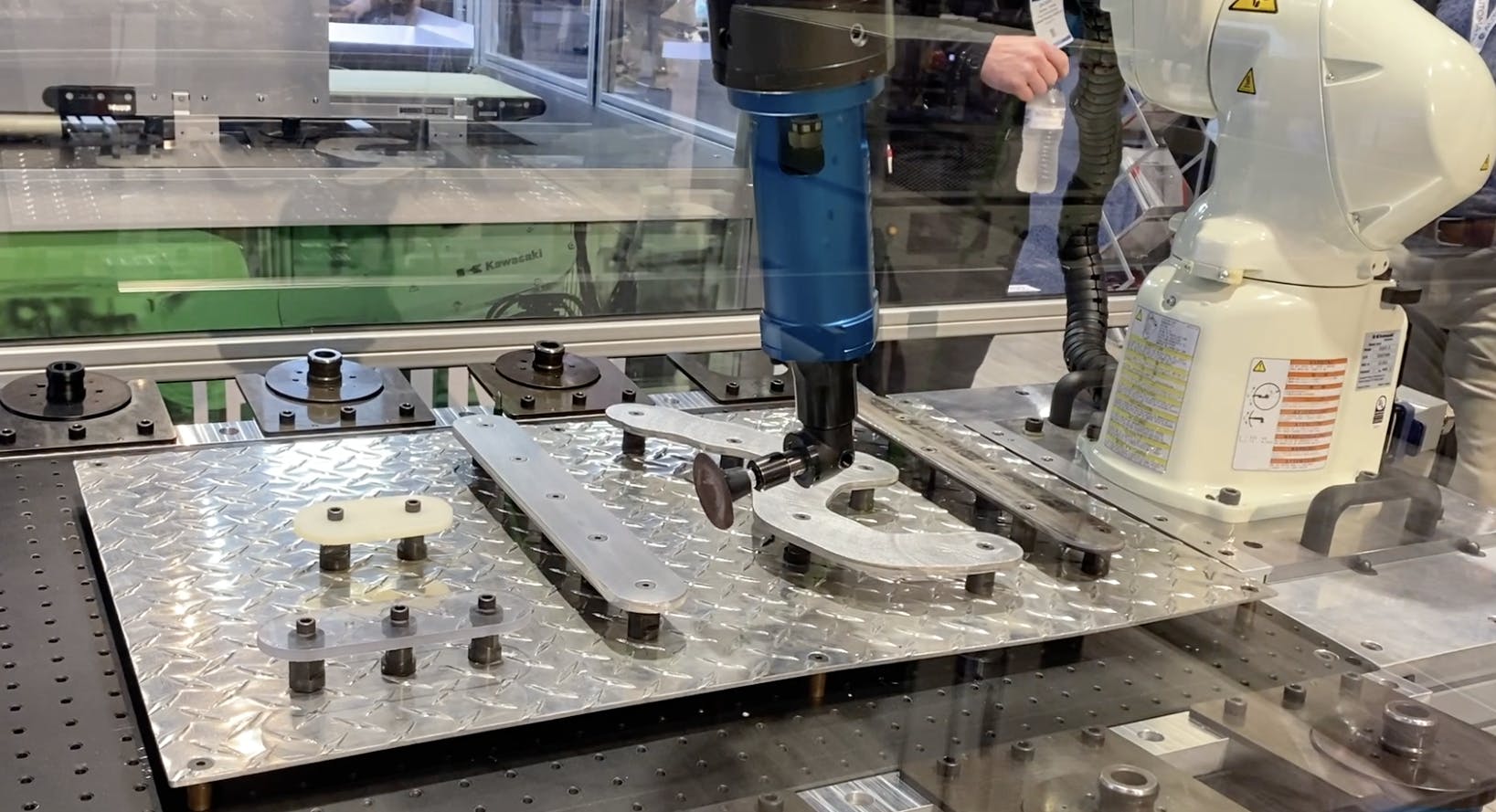 This robot work cell developed by AMT Precision Parts features Kawasaki robots using off-the-shelf tools for applications such as polishing, routing, drilling, grinding and deburring.