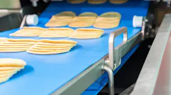 Close up bologna sliced plate on conveyor of automatic slicer machine for industrial food manufacturer