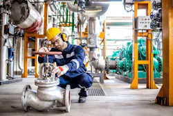 Hardworking industrial technician inspecting high pressure valve inside refinery plant Hardworking industrial technician inspecting high pressure valve inside refinery plant