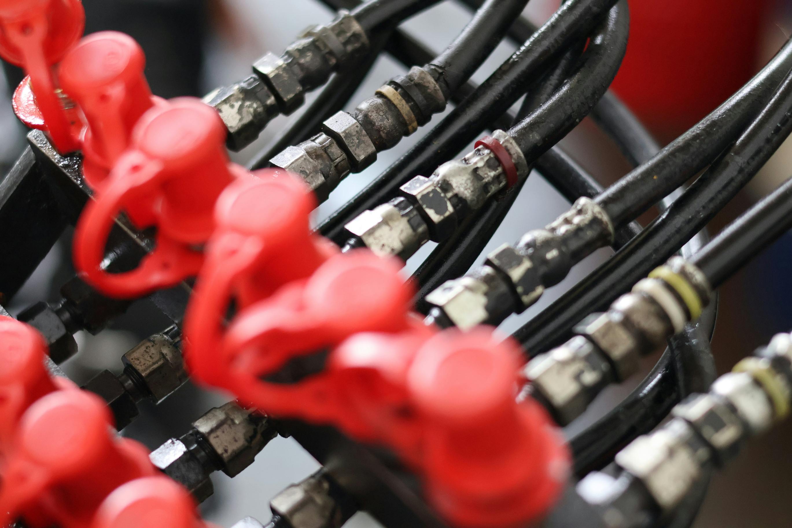 Close up of industrial hydraulic hoses with connectors and red protective dust caps, professional fluid power system for heavy machinery engineering and maintenance.