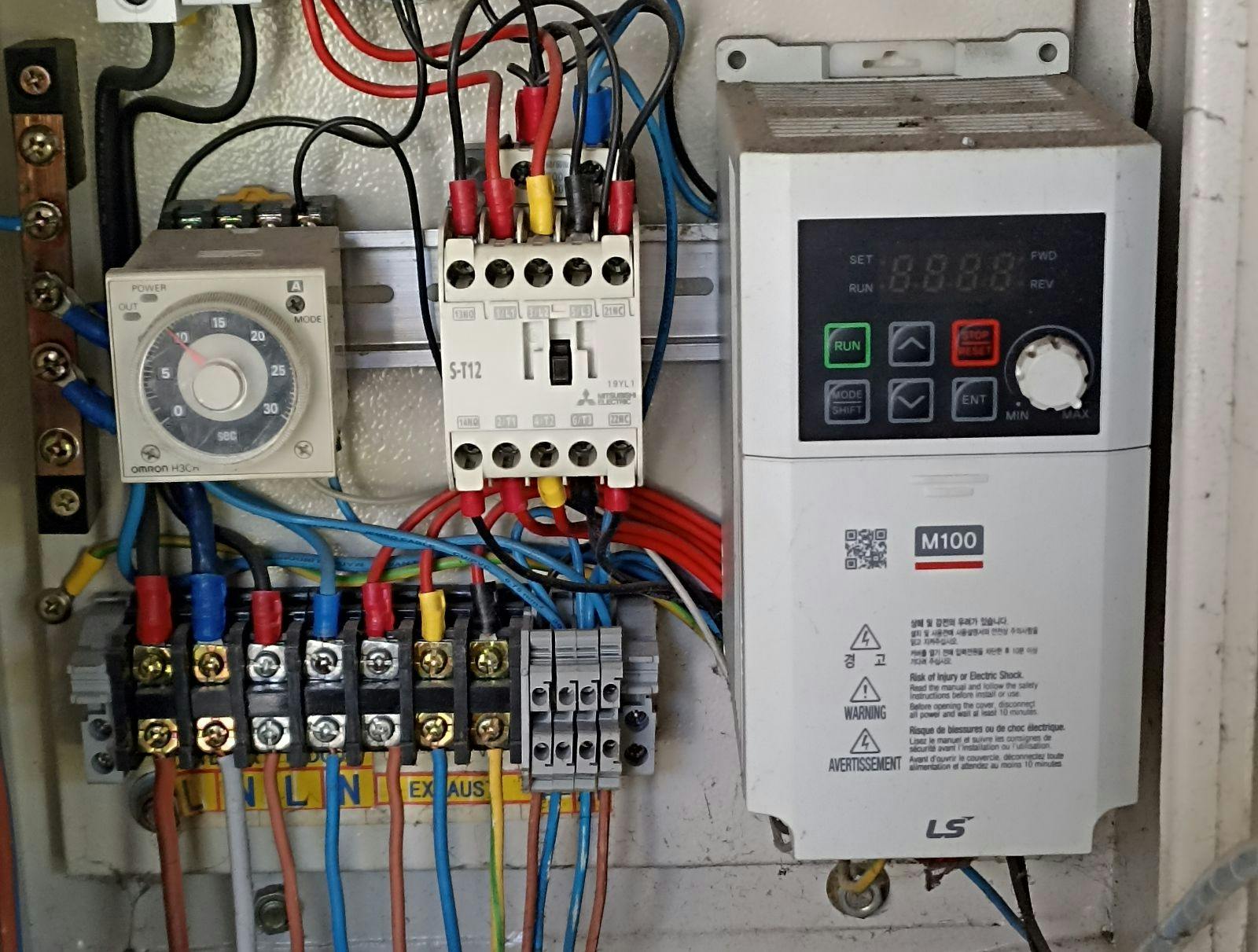 Close-up of an industrial electric control panel, featuring a digital Variable Frequency Drive (VFD), relay, and wiring.